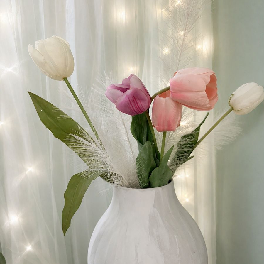 Tulpen in einer weißen Vase vor einem Lichtervorhang